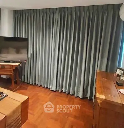 Cozy living room with elegant curtains and wooden furniture, perfect for relaxation.