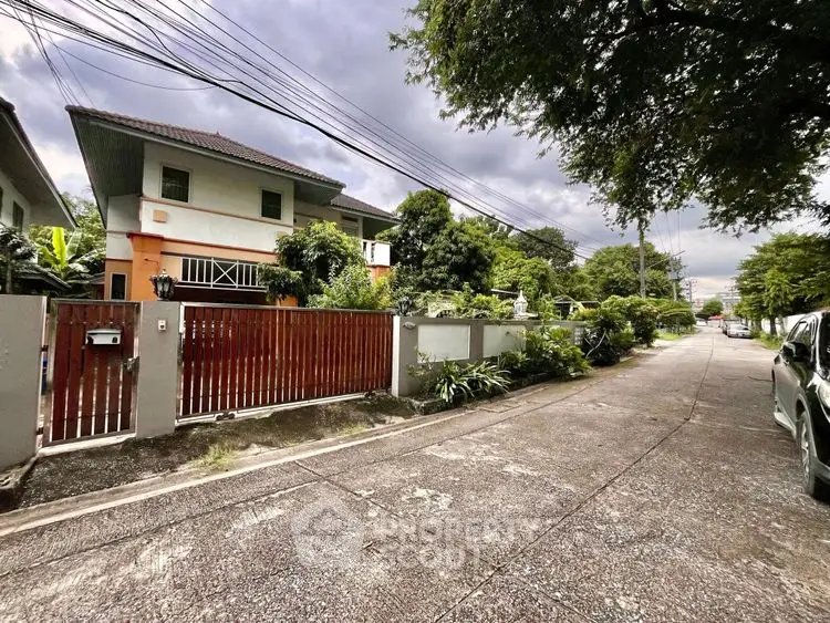 Charming suburban house with lush garden and secure gated entrance on a quiet street.