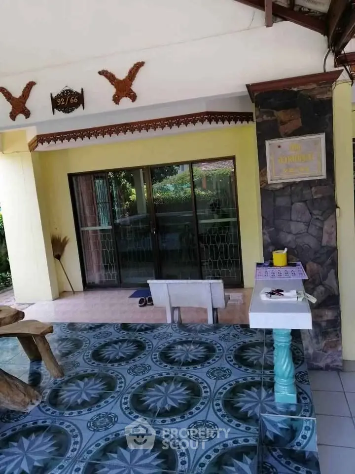 Charming entrance with decorative tiles and sliding glass doors in a serene setting.