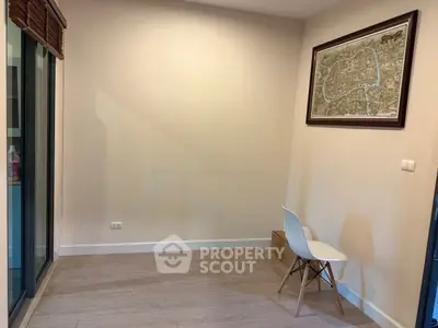 Minimalist room with wooden floor, chair, and framed map on wall