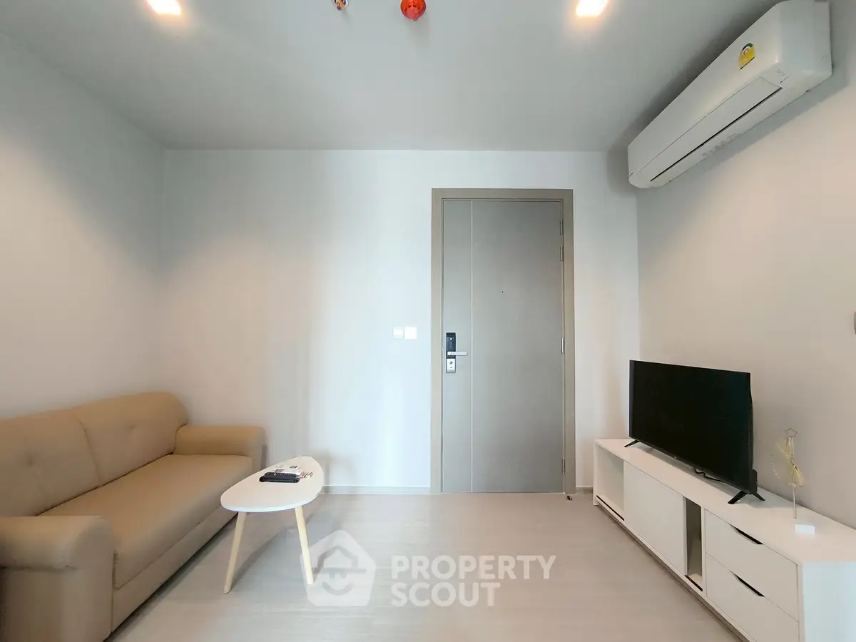 Modern living room with beige sofa, TV, and air conditioning unit.