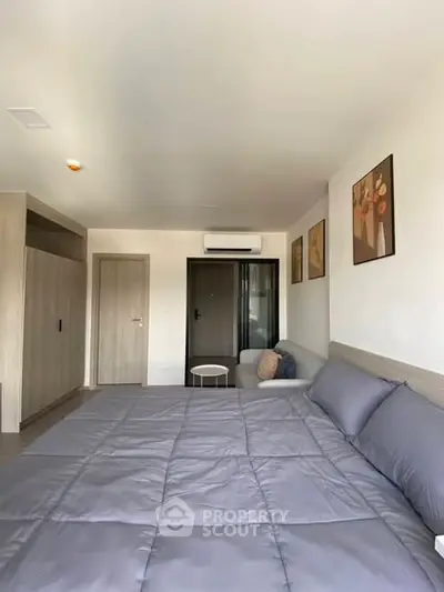 Spacious modern bedroom with stylish decor and cozy seating area, perfect for relaxation.