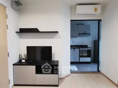 Modern living room with sleek TV stand and view into a compact kitchen area.