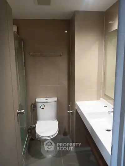 Modern bathroom with sleek fixtures and neutral tones, featuring a spacious sink and glass shower.