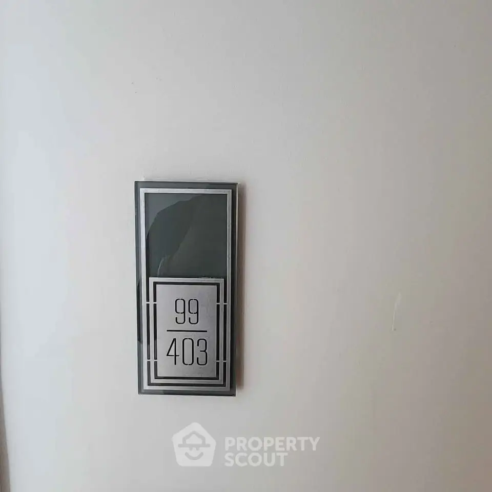 Modern apartment number plaque on white wall, showcasing sleek design and elegance.