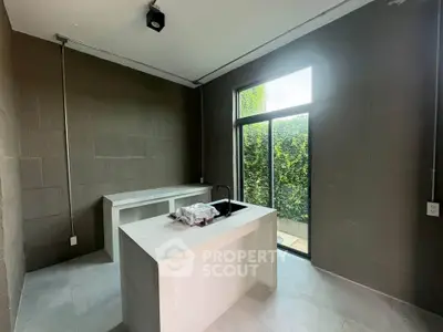 Modern minimalist kitchen with large window and sleek island in a contemporary home.