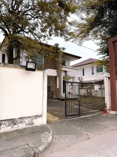 Charming suburban house with gated entrance and lush trees, perfect for family living.