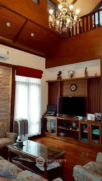 Luxurious living room with high ceiling, elegant chandelier, and wooden accents for a cozy ambiance.