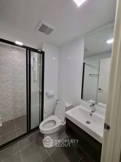 Modern bathroom with sleek design, featuring a glass-enclosed shower and contemporary fixtures.