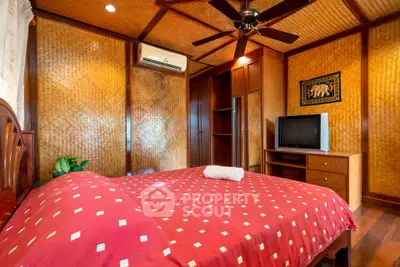Cozy bedroom with wooden decor and modern amenities, featuring a ceiling fan and air conditioning.