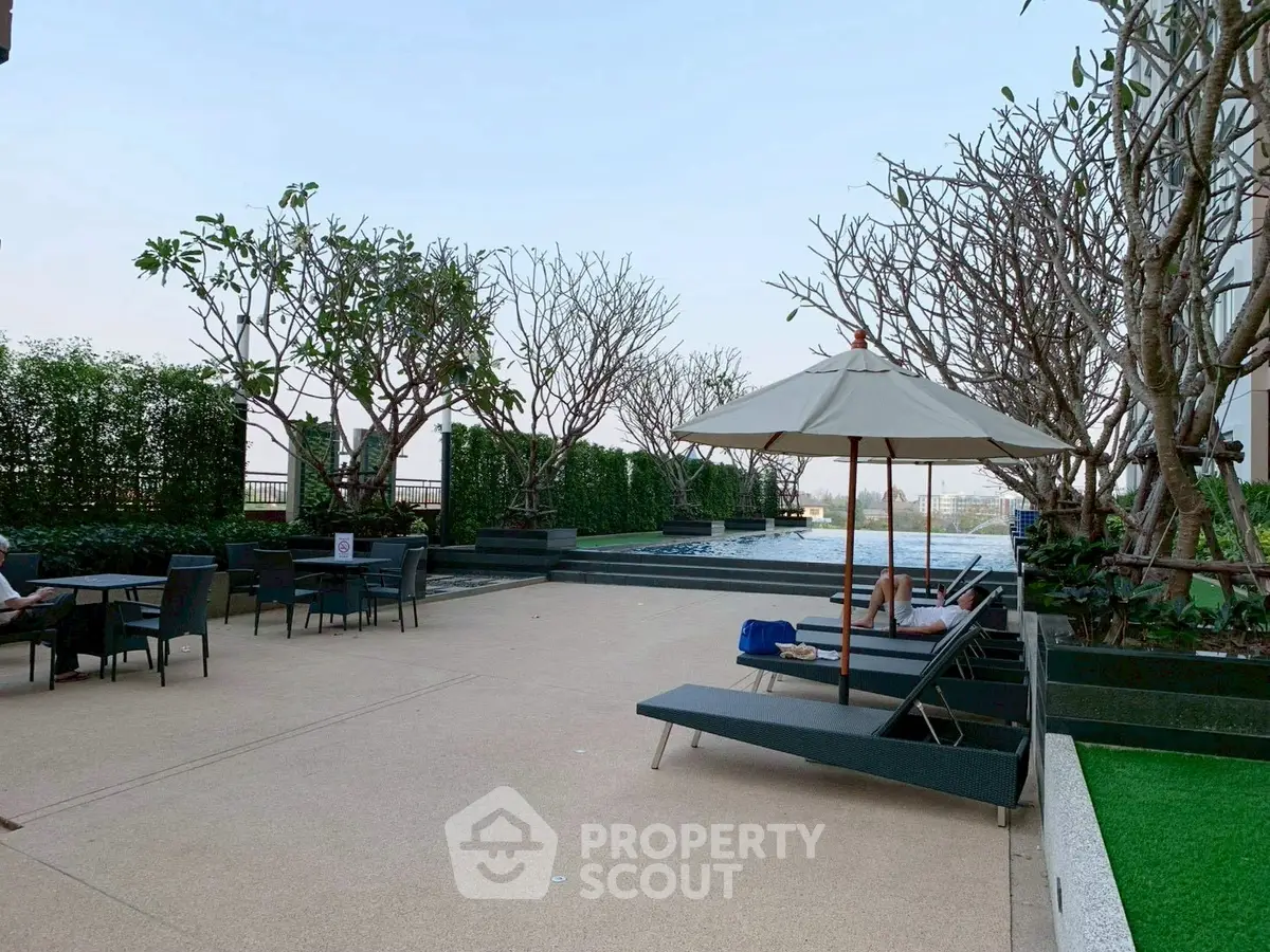 Luxurious rooftop pool area with sun loungers and lush greenery, perfect for relaxation.