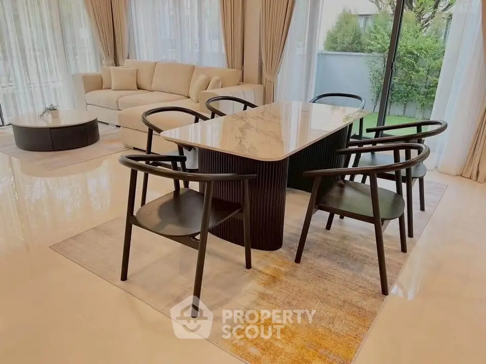 Elegant living room with modern dining set and large windows overlooking garden