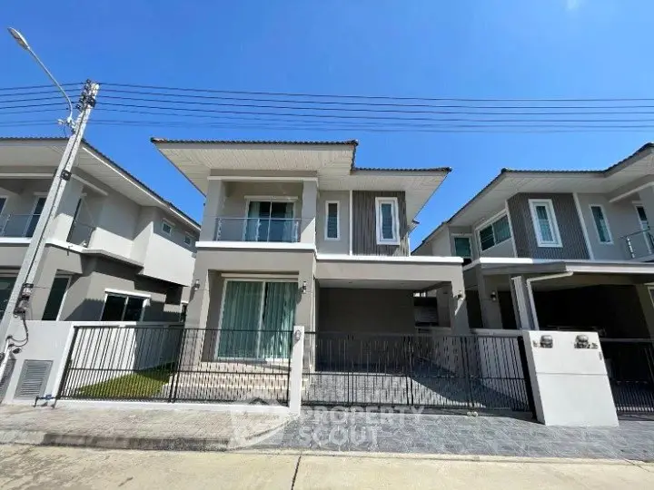 Modern two-story house with sleek design and spacious driveway under clear blue sky.