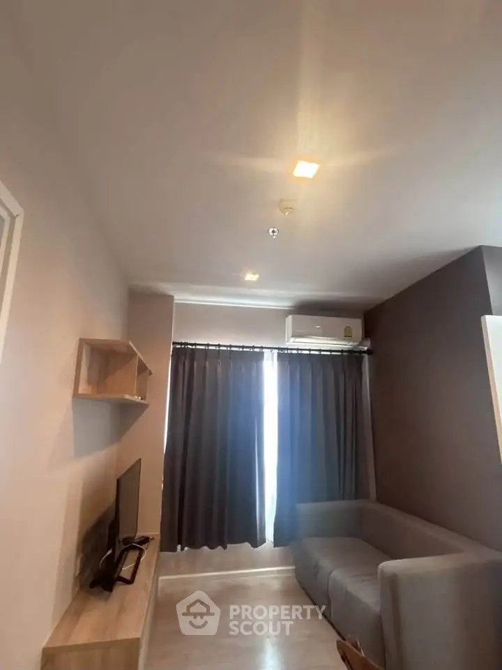 Cozy living room with modern decor and natural light, featuring a comfortable sofa and wall-mounted TV.