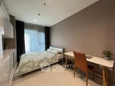 Modern bedroom with stylish decor and workspace, featuring a comfortable bed and natural light.