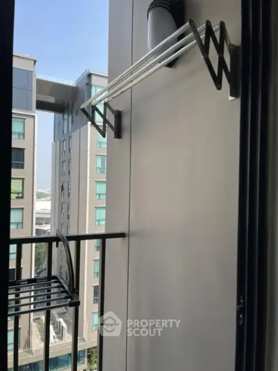 Modern apartment balcony with city view and drying rack, perfect for urban living.