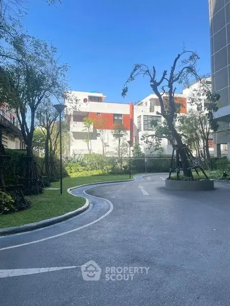 Modern residential building with lush garden and clear blue sky, ideal for urban living.