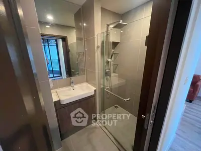 Modern bathroom with glass shower and sleek sink in contemporary apartment.