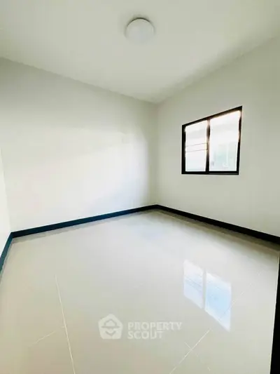 Spacious empty room with glossy tiled floor and large window, perfect for customization.
