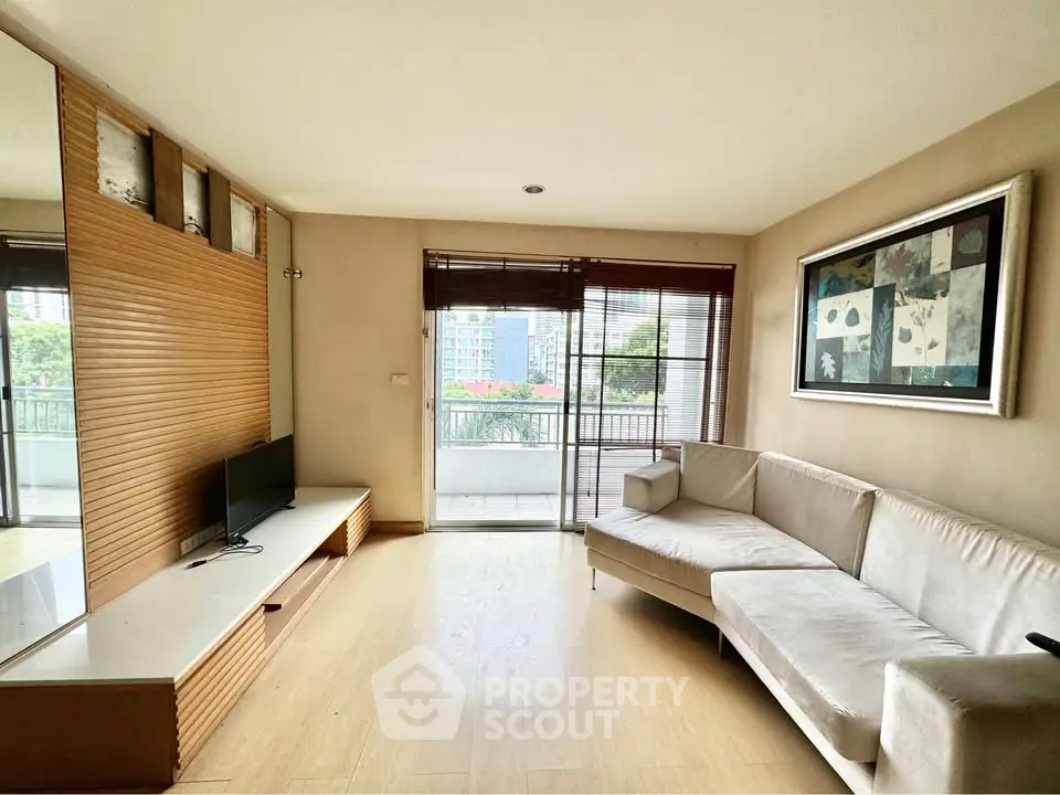 Spacious living room with modern decor and large windows opening to a balcony with city view.