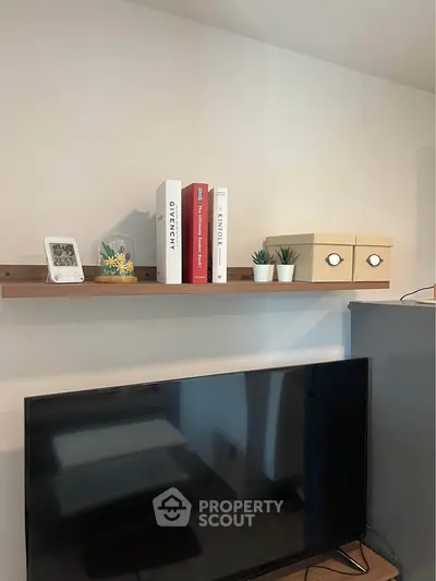 Modern living room with stylish shelf decor and flat-screen TV setup.