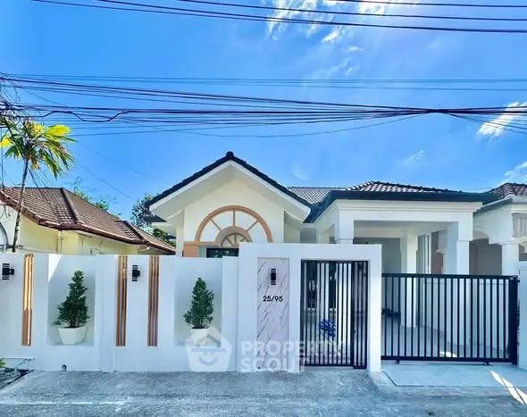 Charming single-story house with modern gate and lush greenery under a clear blue sky.
