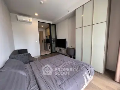 Modern bedroom with sleek design, featuring a cozy bed, stylish wardrobe, and a compact living area with TV.