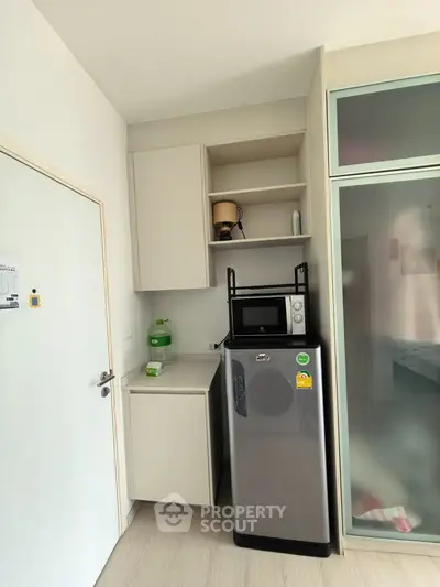 Compact kitchen with modern fridge and microwave in cozy apartment