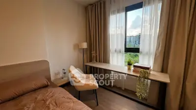 Cozy bedroom with modern decor and large window offering a serene view.