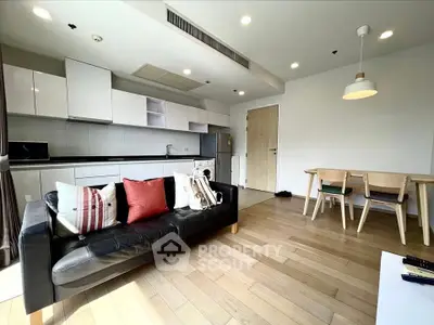 Modern open-layout living room with sleek kitchen and dining area, featuring stylish decor and ample natural light.
