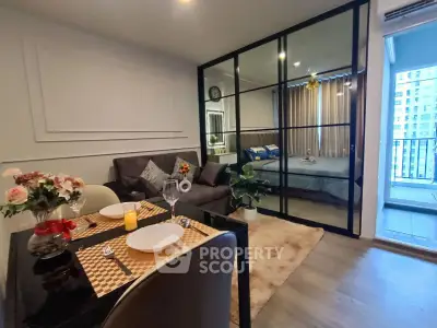 Modern apartment with open living and dining area, glass partition to bedroom, and balcony view.