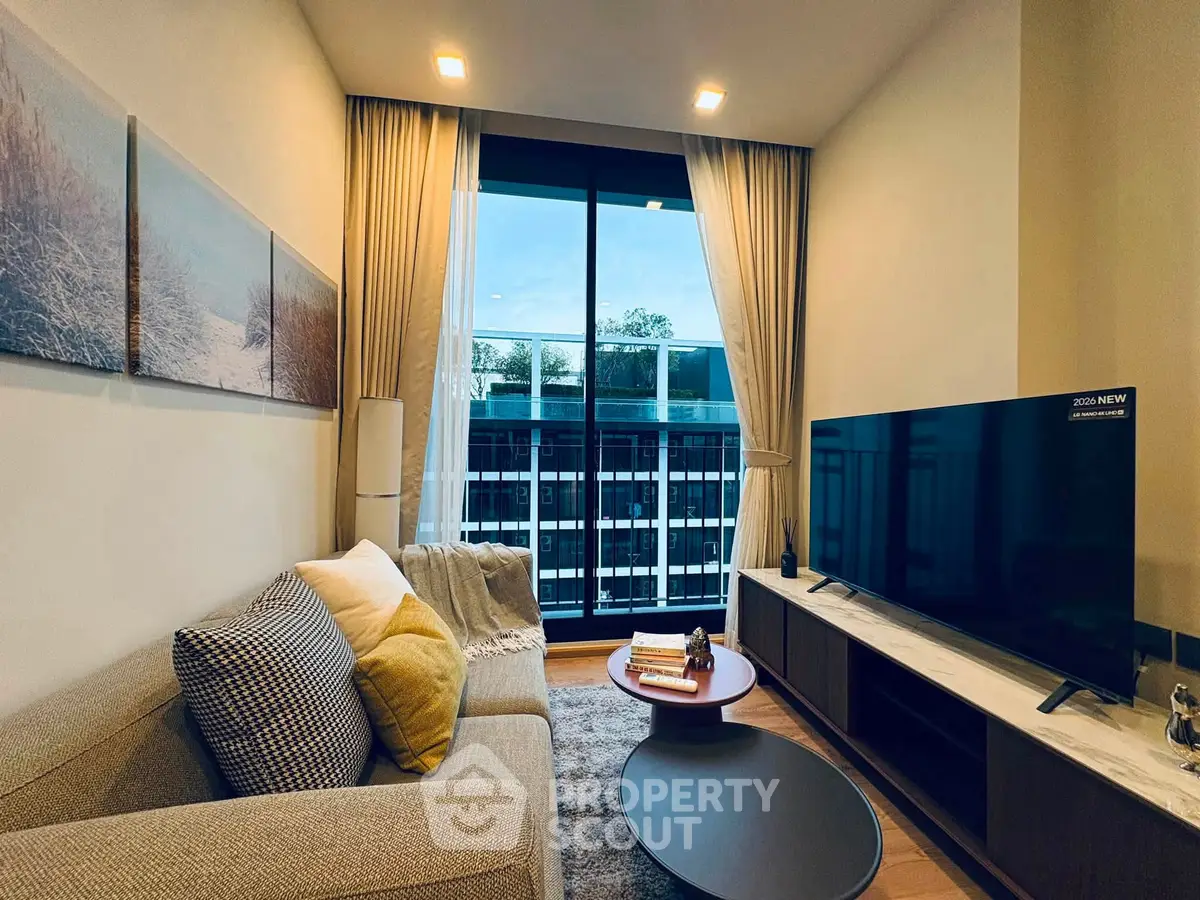 Modern living room with large TV, cozy sofa, and floor-to-ceiling windows offering a stunning view.