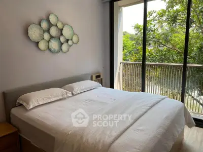 Bright bedroom with large window and balcony view, featuring modern decor and lush greenery outside.