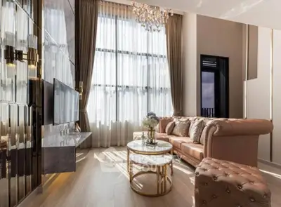 Luxurious living room with high ceilings, elegant chandelier, and plush leather sofa in a modern apartment.