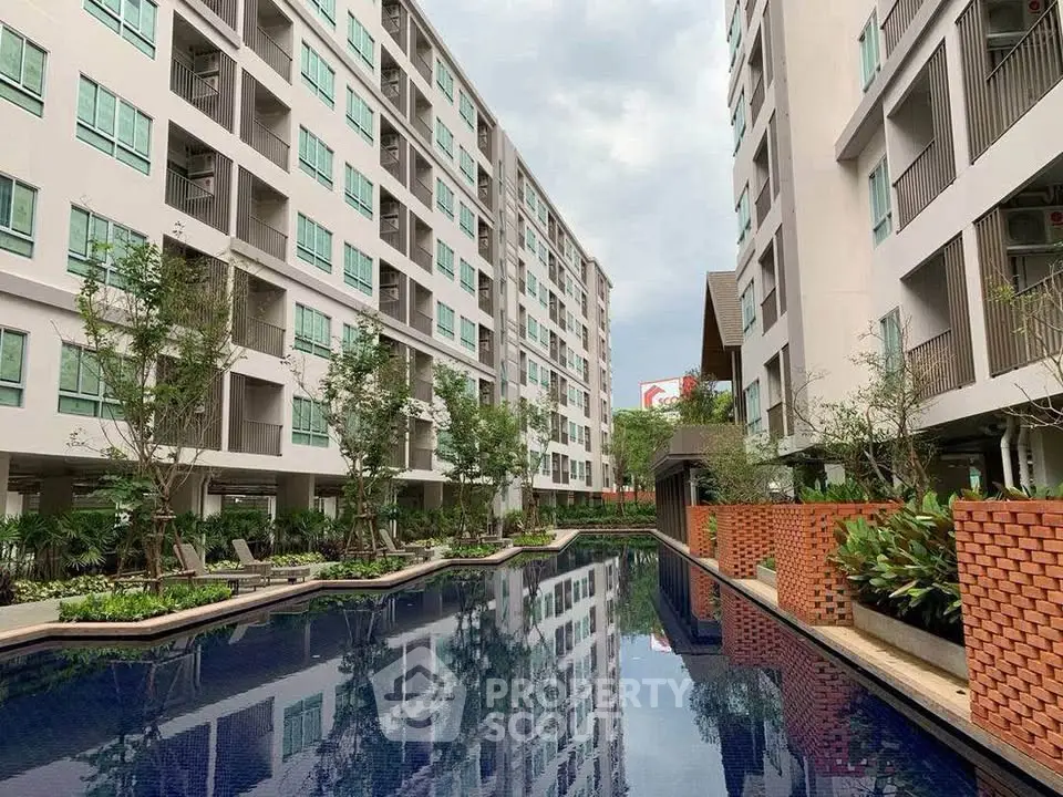 Modern apartment complex with a luxurious swimming pool and lush greenery.