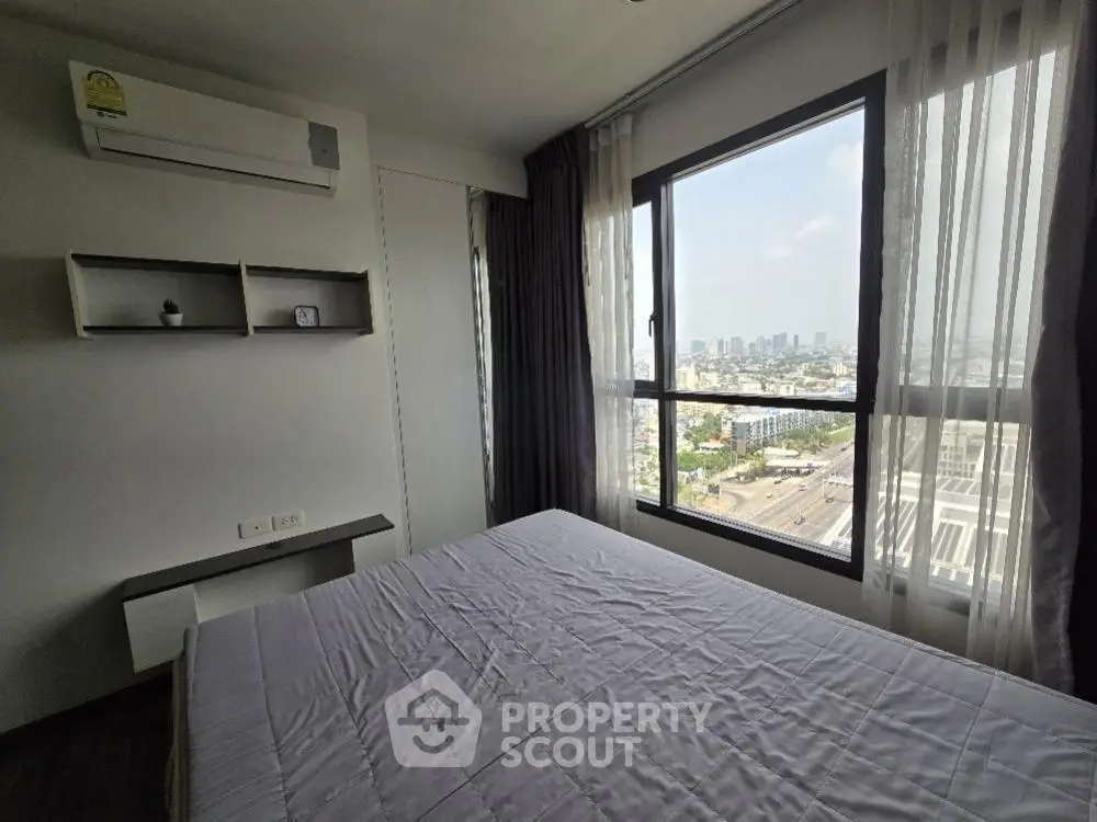 Spacious bedroom with large window offering stunning city views in modern apartment.