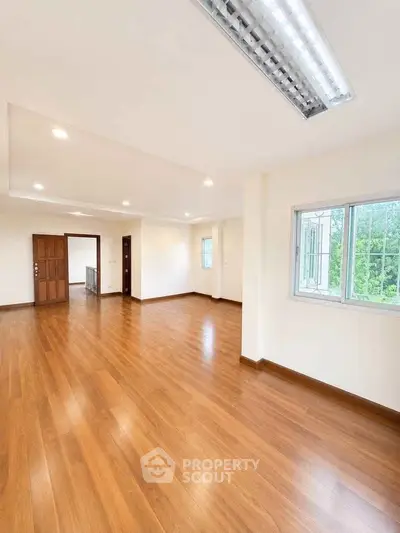 Spacious empty living room with wooden flooring and large window