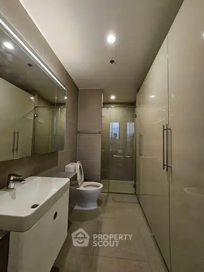 Modern bathroom with sleek fixtures and spacious shower in contemporary apartment.