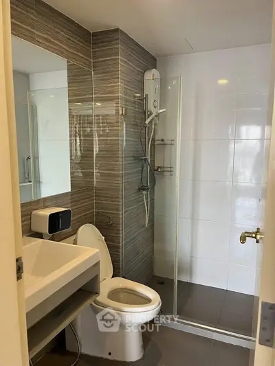 Modern bathroom with sleek design, featuring a glass shower enclosure and contemporary fixtures.
