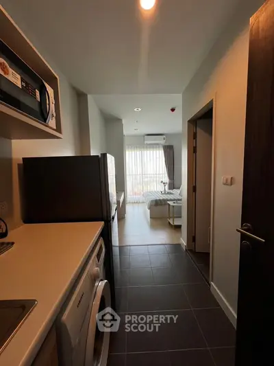 Modern apartment interior with kitchen and living area, featuring sleek appliances and large windows.