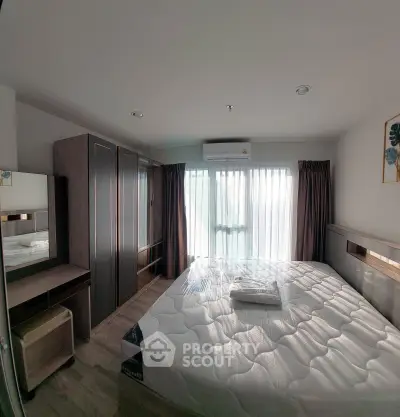 Spacious bedroom with modern furnishings and large window offering natural light.