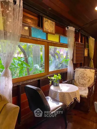 Charming rustic living room with vintage decor and lush garden view through colorful windows.