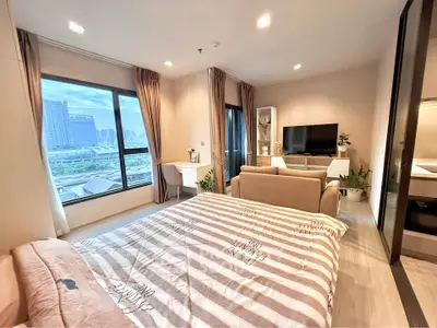 Modern bedroom with city view, cozy seating area, and stylish decor