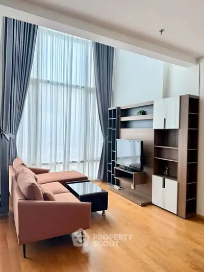 Spacious living room with high ceilings and modern furniture, featuring a large window with elegant curtains.