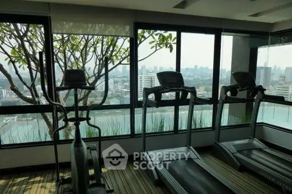 Modern gym with city view and exercise equipment in high-rise building.