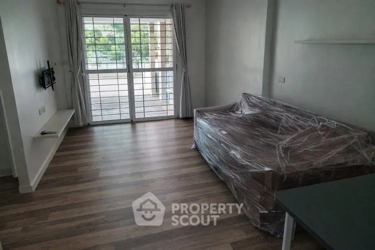 Spacious living room with large windows and modern flooring, perfect for natural light lovers.