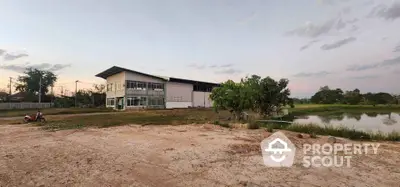 Spacious industrial building with adjacent pond and open land, ideal for development.