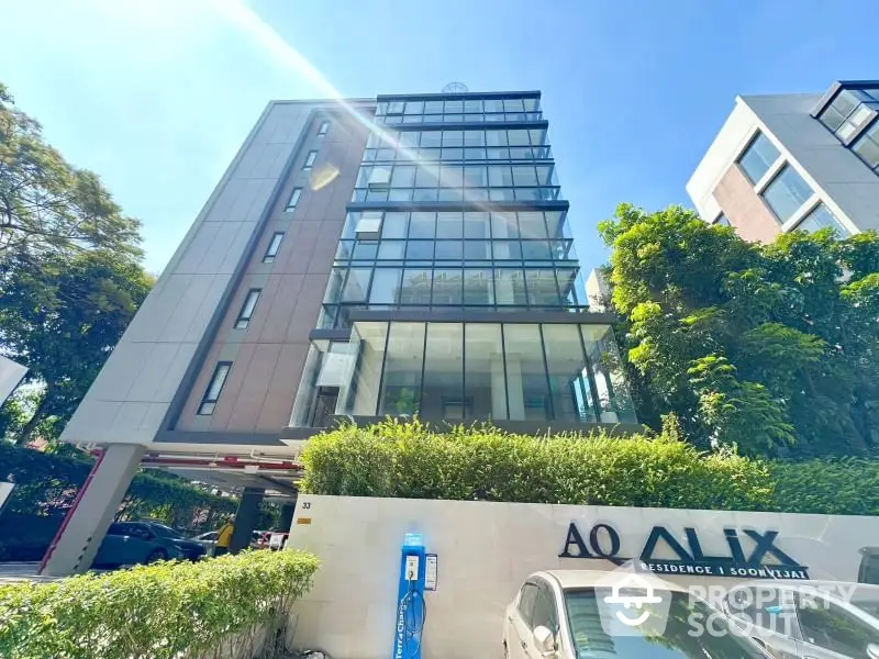 Modern residential building with glass facade and lush greenery in urban setting