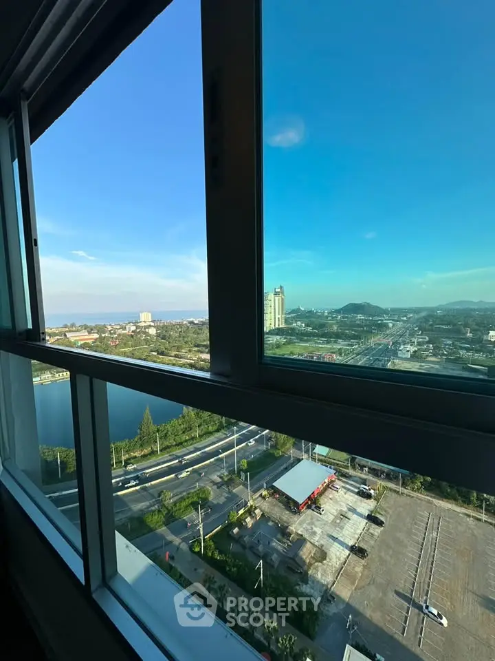 Stunning high-rise view from a modern apartment window overlooking cityscape and serene water body.