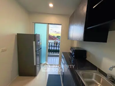 Modern kitchen with sleek cabinets and balcony view in a stylish apartment.